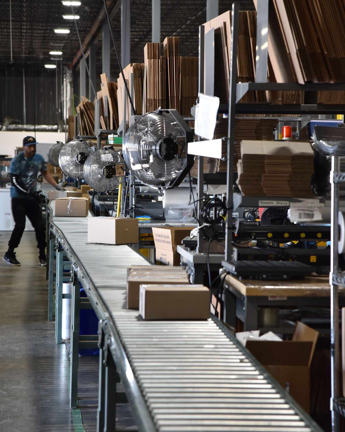 Pack line with roller conveyors and pack stations, a team member walking the line