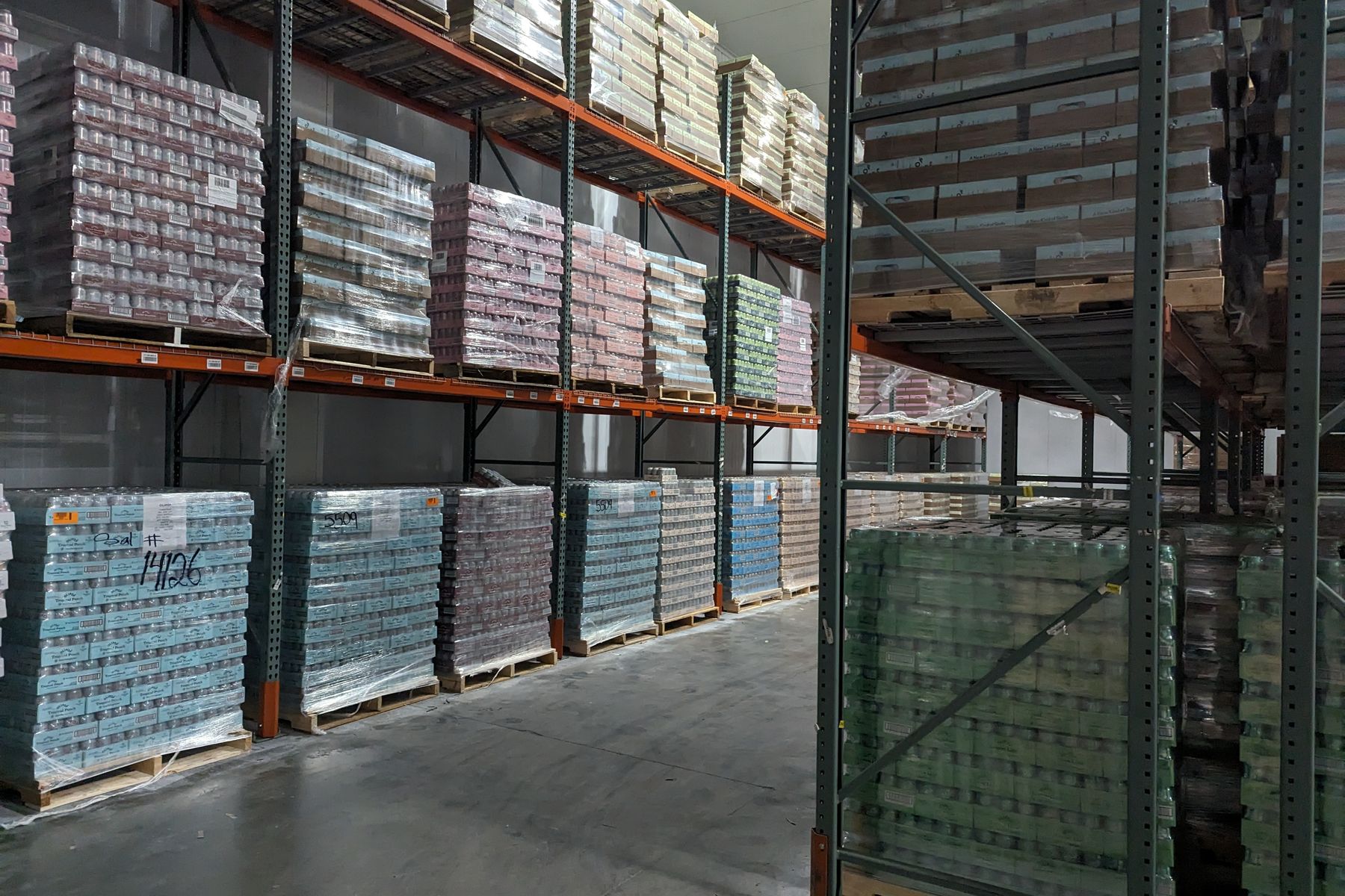 Pallets of packaged food and beverage cases stored on warehouse racking