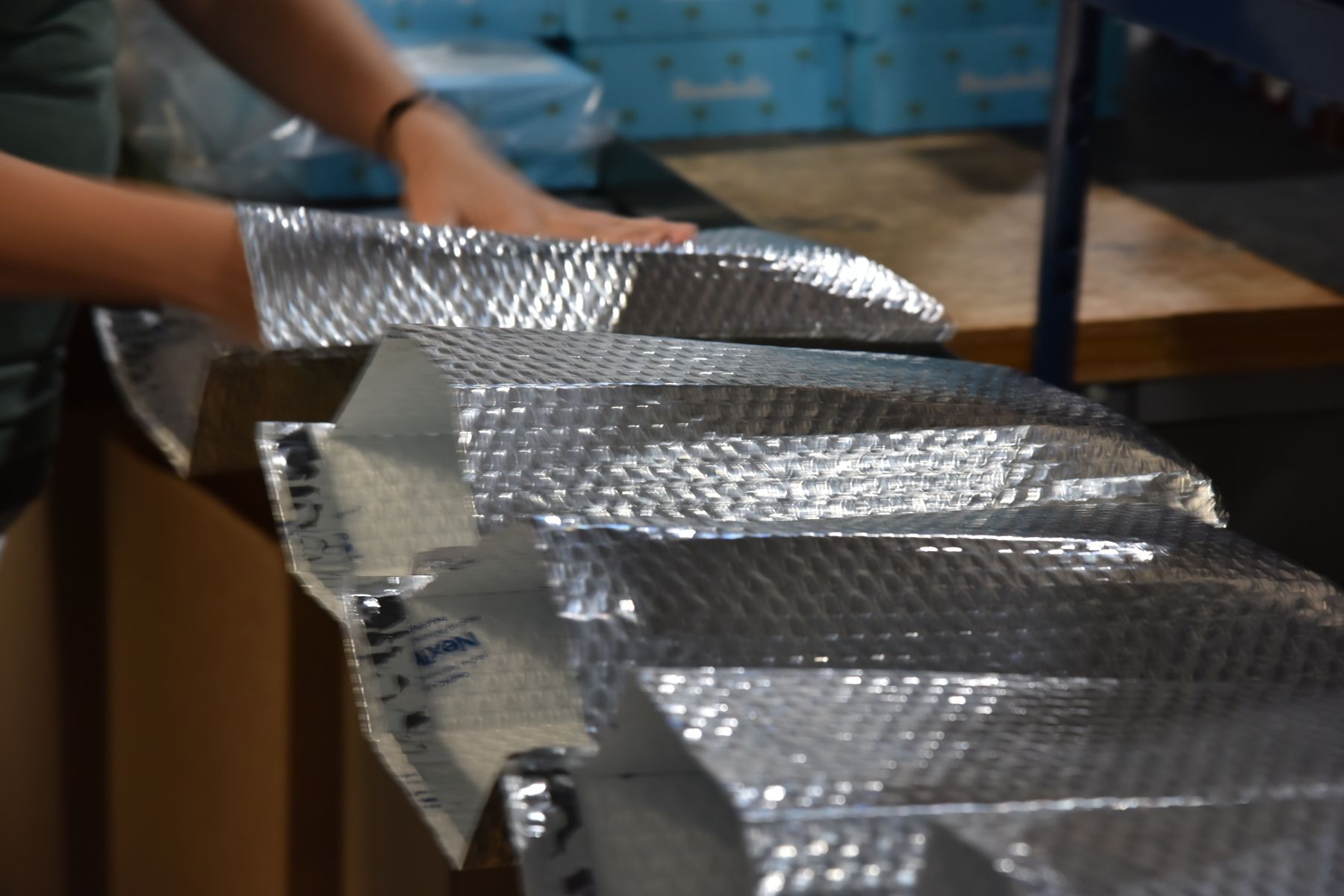 Hands laying out insulated mailers for a kitting and packing job