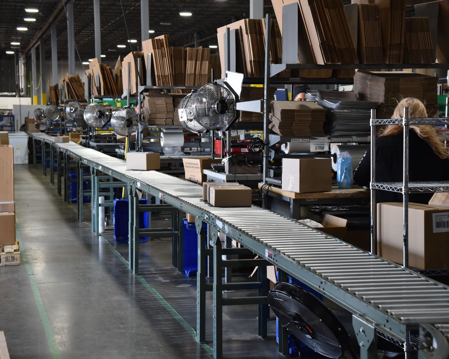 Long pack line with roller conveyors and a team member packing at her station