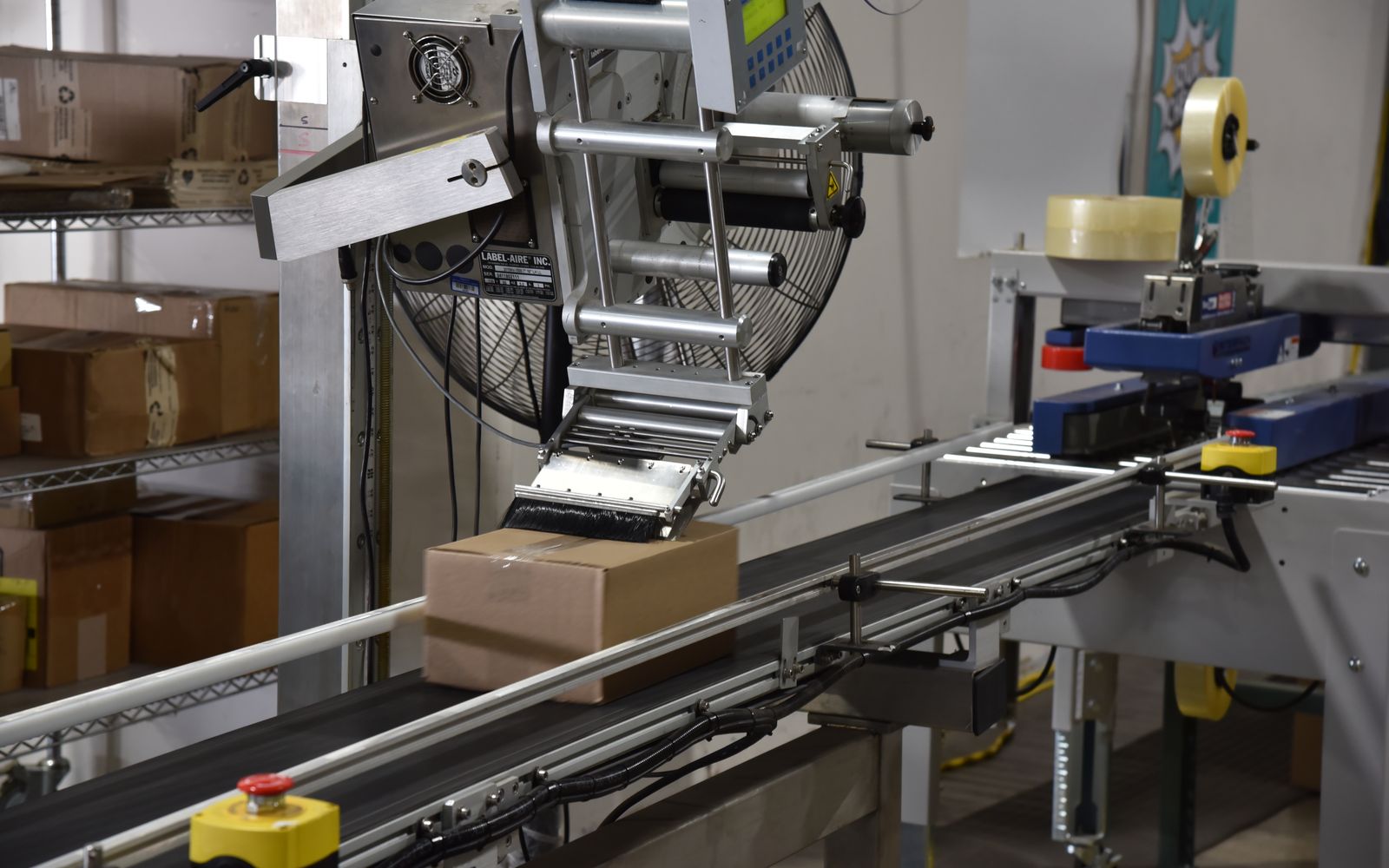 Automatic label applicator labeling a box on the conveyor