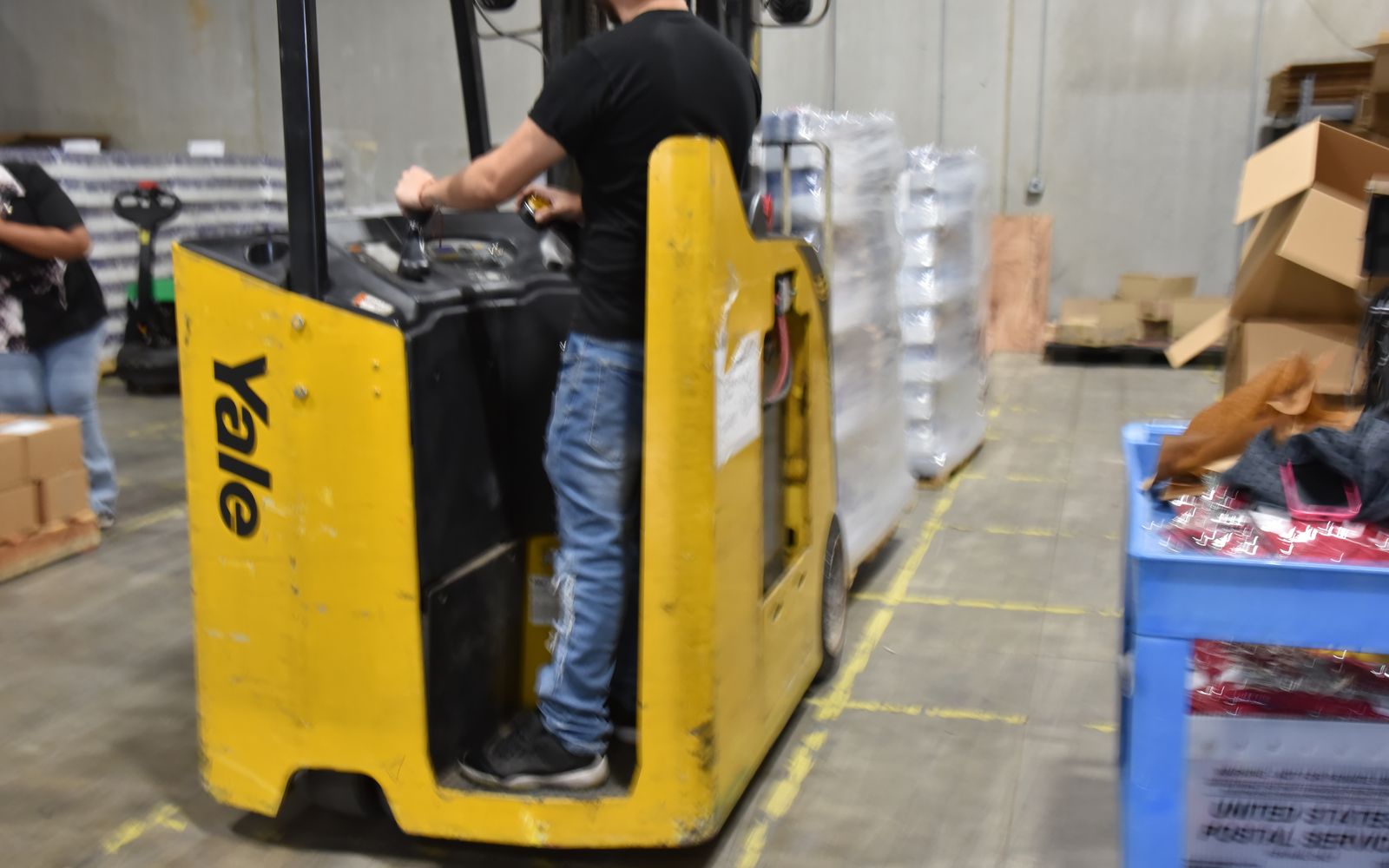 Team member driving an order picker past pallets in the warehouse