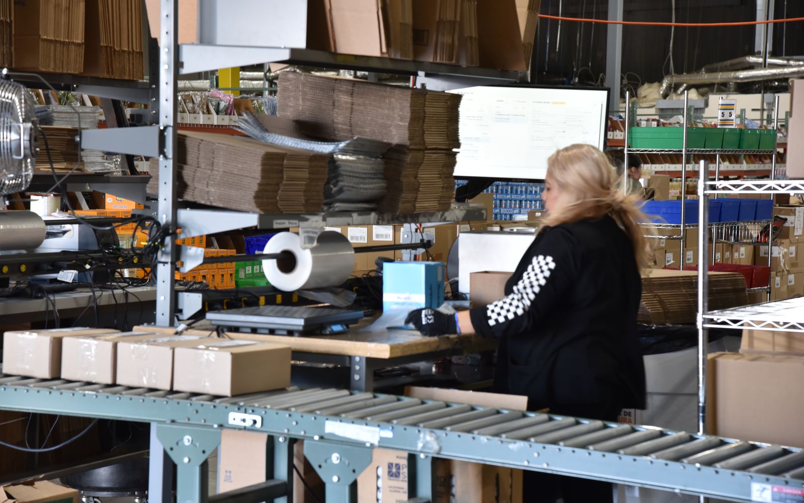 Team member packing orders at a station with a live order screen